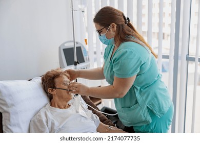 Nurse Putting On A Breathing Mask On A Female Patient With Covid-19. High Quality Photo