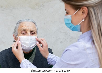 Krankenpflege mit chirurgischer Maske auf ältere kranke Frau - Schutzprotokoll gegen Coronavirus