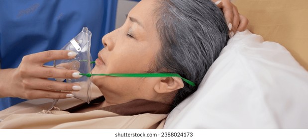 Nurse putting oxygen mask with patient elderly woman on bed for diagnose and healing in hospital, specialist doctor giving oxygen mask with senior emergency for recovery in clinic, medical concept. - Powered by Shutterstock