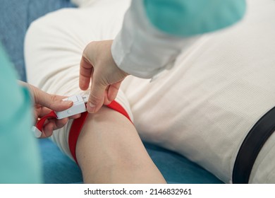 Nurse Putting Tourniquet On Male Arm In Hospital