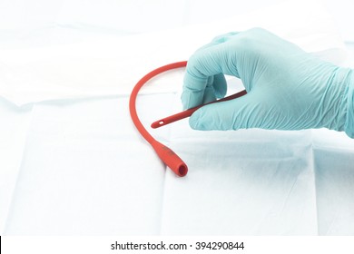 Nurse removes red rubber catheter from sterile package.