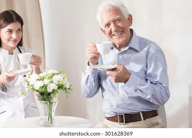 Nurse And Retiree Drinking Coffee At Home