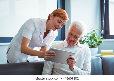 Nurse And Senior Man Using A Digital Tablet In A Retirement Home