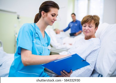 Nurse Showing Clipboard To Patient In Ward At Hospital