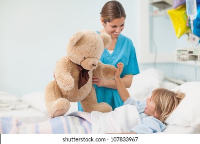 Nurse Showing A Teddy Bear To A Child In Hospital Ward