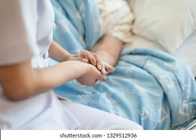 Nurse Sitting On A Hospital Bed Next To An Older Woman Helping Hands, Care For The Elderly Concept