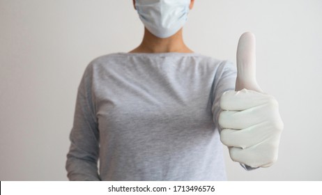 A Nurse With A Surgical Mask And Blue Rubber Gloves Gives Thumbs Up.