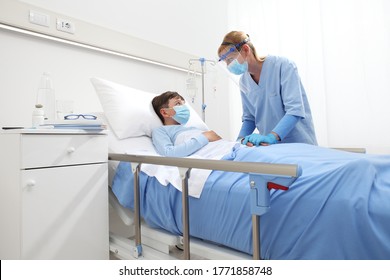 Nurse Takes Care Of The Patient Child In Hospital Bed, Wearing Protective Masks, Corona Virus Covid 19 Protection Concept, 