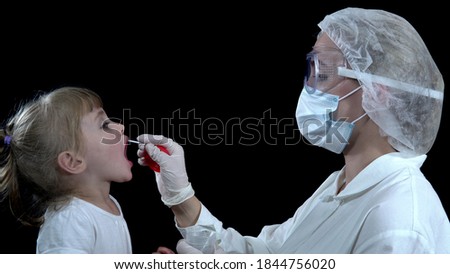A nurse takes a covid-19 test from a girl. The child takes the analysis on a black background