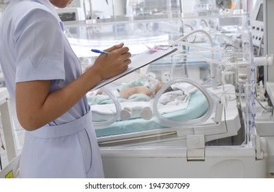 The Nurse Takes Note Of The Data Pediatric Patients In Incubators In The ICU