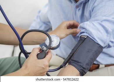 Nurse Taking The Blood Pressure Of Elderly Man