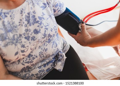 Nurse Taking Blood Pressure With A Stethoscope From A Senior Woman In The Hospital - Female Doctor Checking Vital Signs Of A Elderly Patient In A Private Clinic