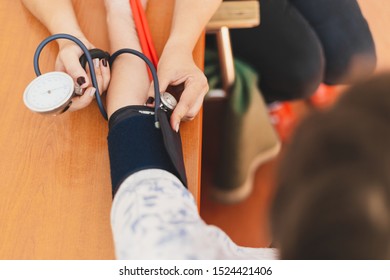 Nurse Taking Blood Pressure From A Young Woman With Stethoscope In The Hospital - Female Medical Assistant Checking Vital Signs And Health Of A Patient In A Private Clinic