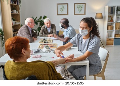 Nurse Taking Blood Test From Senior Woman During Medical Exam In Nursing Home