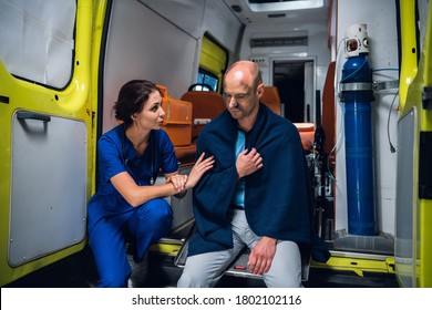 Nurse talking friendly to an injured man in a blanket in an ambulance car. - Powered by Shutterstock