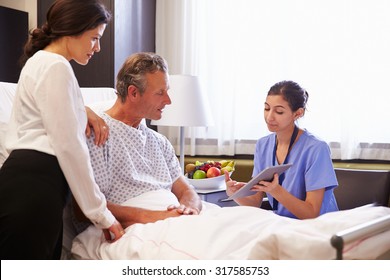 Nurse Talking To Male Patient And Wife In Hospital Bed