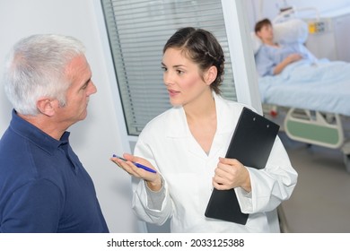 Nurse Talking To Relative Outside Of Hospital Room