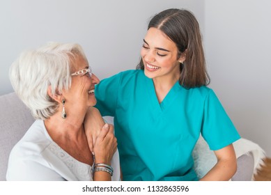 Nurse Talking With Senior Woman Sitting In Chair On Home Visit. Female Community Nurse Visits Senior Woman At Home. Female Support Worker Visits Senior Woman 