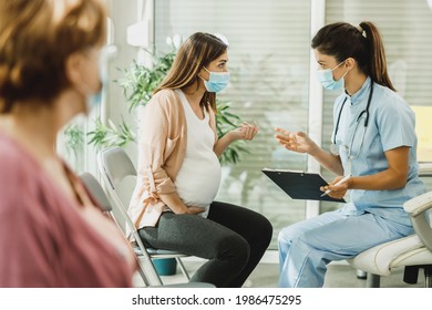 Nurse talking to young pregnant woman before gynecologist check up at hospital waiting room.