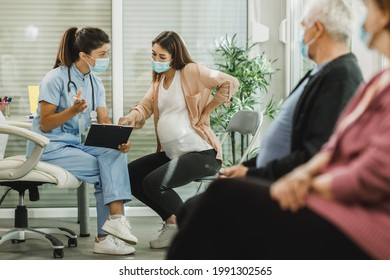 Nurse talking to young pregnant woman before covid-19 vaccine at hospital waiting room. - Powered by Shutterstock