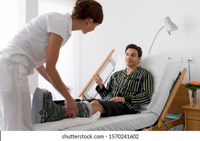 Nurse Tending To Man With Broken Leg In Hospital Bed