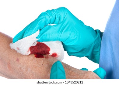 A nurse tends to a bloody wound on an alderly woman's arm