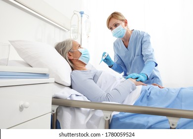 Nurse With Thermometer Measures Fever On Elderly Woman Patient Lying In The Hospital Room Bed, Wearing Protective Gloves And Medical Surgical Mask, Coronavirus Covid 19 Protection Concept