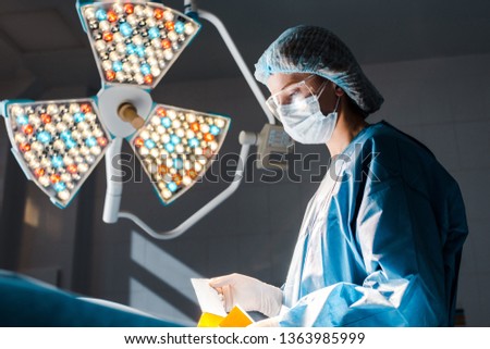 nurse in uniform and medical cap holding strip in operating room 