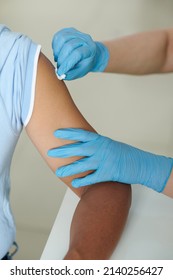 Nurse Using Cotton Swab Moistened With Alcohol To Wipe Arm Of Patient Before Vaccination