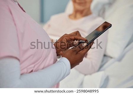 Nurse using digital tablet while standing beside patient in hospital bed, focusing on device. Patient smiling and appearing comfortable with professional care