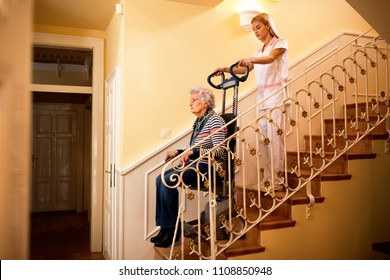 Nurse Using Machine For Climbing To The Stairs And Helps Old Mature Senior Disabled Woman At Nursing Home, Care Concept