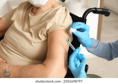 Nurse vaccinating senior woman in wheelchair at home, closeup - Powered by Shutterstock