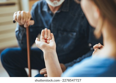 Nurse visiting mature patient at home. She is holding pill bottle and talking to patient how to use it. Home care for old people. Senior patient holds prescription and talks with smiling nurse - Shutterstock ID 2278547727