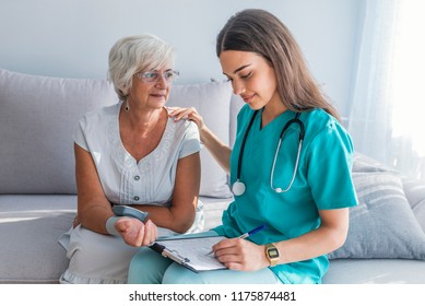 Nurse Visiting Senior Woman For Check Up. Young Nurse Measuring Blood Pressure Of Elderly Woman At Home. Happy Senior Woman Having Her Blood Pressure Measured In A Nursing Home By Her Caregiver