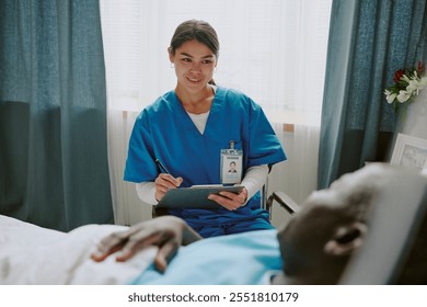 Nurse wearing blue scrubs is interacting with an elderly patient lying in a hospital bed, using a tablet for medical information - Powered by Shutterstock