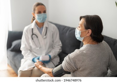 Nurse Wearing Mask Caring About Elderly Female Patient At Home During Pandemic Period, The Doctor Monitoring Blood Pressure Of Senior Female With Tonometer, On-site Doctor