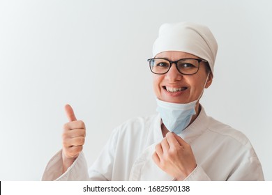 Nurse Wearing A Mask Smiling, Raising Her Thumb Up As A Symbol That All Is Well, Medical Concept