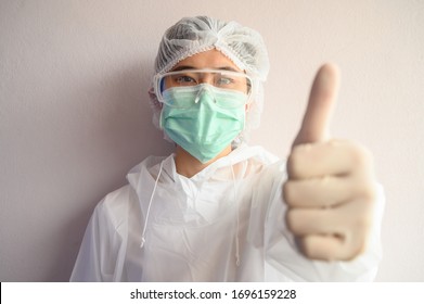 Nurse Wearing PPE Suit With Mask For Protect Virus And Showing Thumbs Up. In Coronavirus Pandemic Outbreak We Should Support And Encourage Healthcare Worker By Stay Home And Listen To Medical Advice.