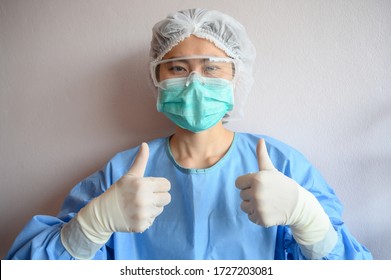 Nurse Wearing Scrubs With Mask For Protect Virus And Showing Thumbs Up. In Coronavirus Pandemic Outbreak We Should Support And Encourage Healthcare Worker By Stay Home And Listen To Medical Advice.