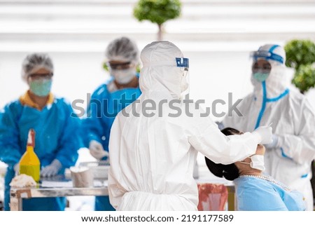A nurse in white gown and face shield is taking nasal swab sample for patient.