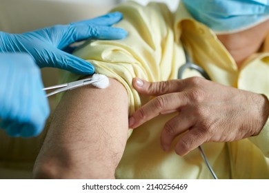 Nurse Wiping Injection Site On Arm Of Patient With Cotton Ball Before Vaccinate Him Against Coronavirus