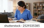 Nurse, woman and studying with books at desk for medical research, information and knowledge. Home, healthcare and reading with laptop in living room for diagnosis reference, guide and treatment plan