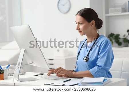 Nurse working on computer at table in clinic