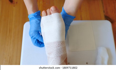 Nurse Wraps A Bandage At The Wounded Foot