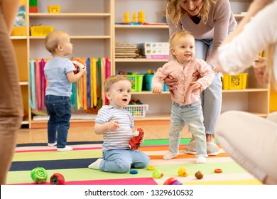 Nursery babies play with carers or mothers on floor in day care centre