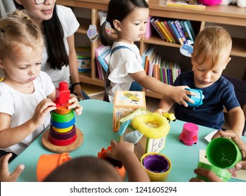 Nursery children playing with teacher in the classroom