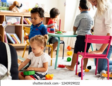 Nursery children playing with teacher in the classroom - Shutterstock ID 1243929022