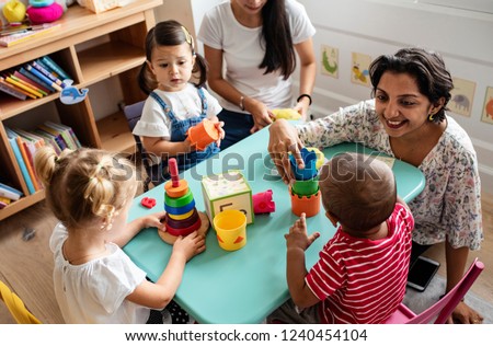 Nursery children playing with teacher in the classroom