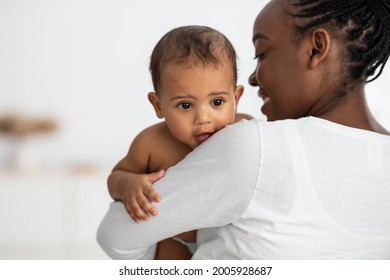 Nursery And Maternity Concept. Back View Of Happy African American Woman With Afro Hair Holding And Hugging Her Small Kig, Enjoying Spending Time With Lovely Baby, Singing Lullaby To Sleep