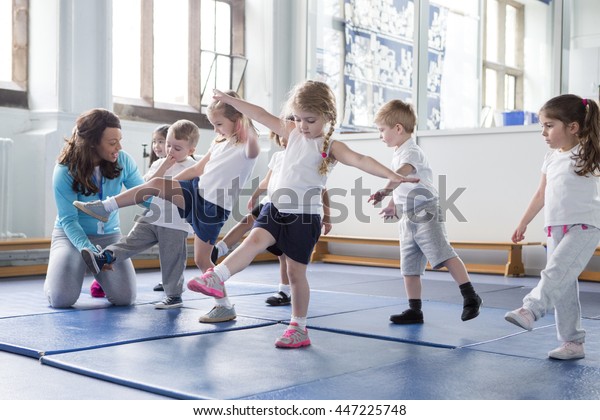 Nursery teacher helping one of her students\
during a physical education\
lesson.